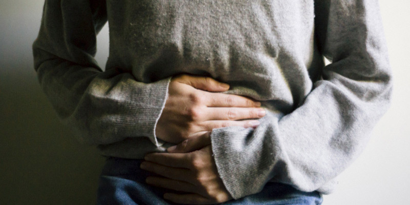 a woman holding her lower stomach a woman holding her lower stomach