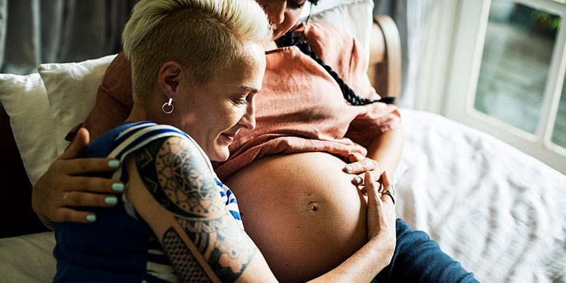 A woman embracing her partners pregnant belly A woman embracing her partners pregnant belly