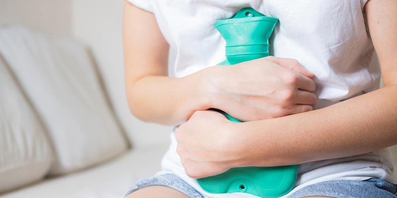 A woman holding a hot water bottle on her stomach A woman holding a hot water bottle on her stomach