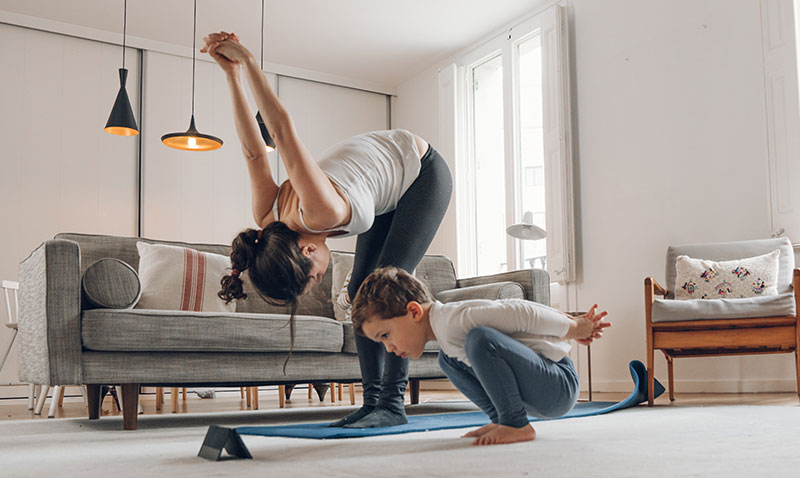 woman exercising at home with her young son woman exercising at home with her young son