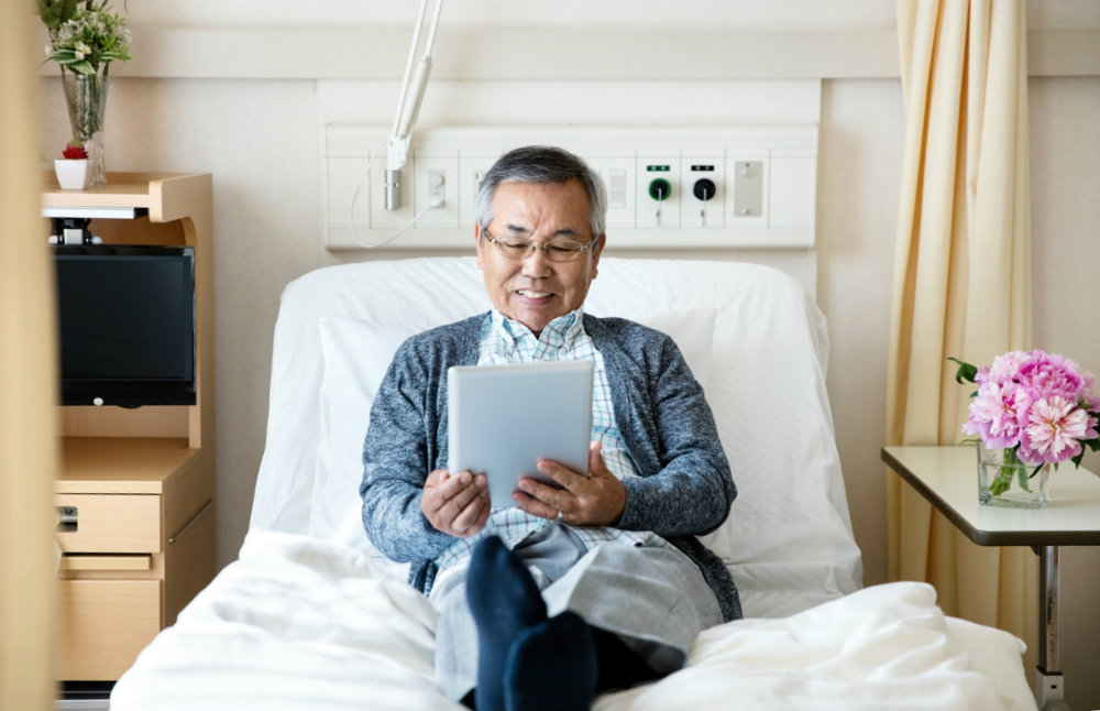 A patient relaxing on hospital bed reading A patient relaxing on hospital bed reading